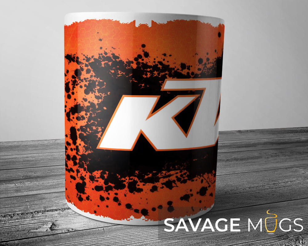 White ceramic mug featuring KTM logo with orange grunge racing design